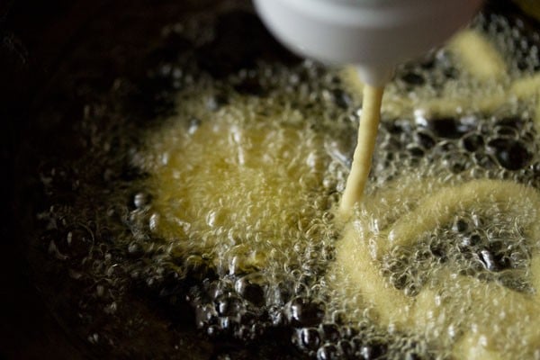 squeezing jalebi batter into oil in concentric circles