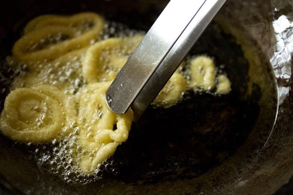 turning jalebi with tongs