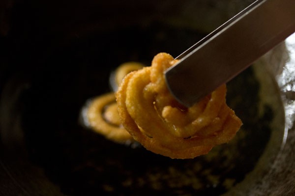 fried jalebi being removed from oil after cooking to golden brown