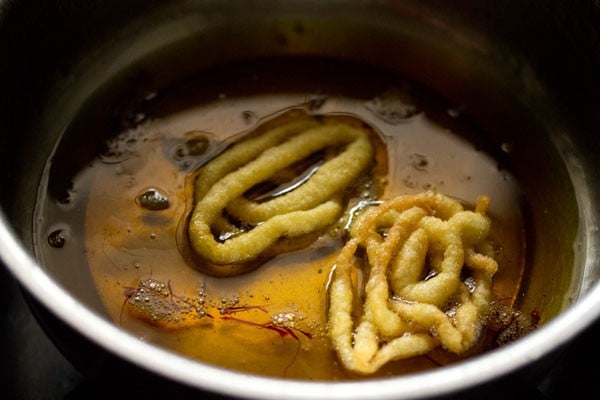 soaking fried jalebi in sugar syrup