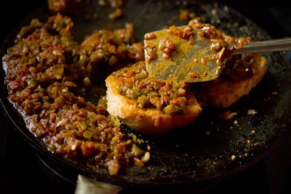 spreading masala on the toasted pav. 