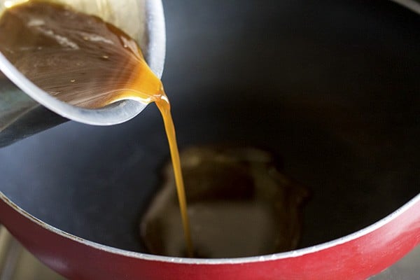 pouring clean jaggery solution in a pan. 