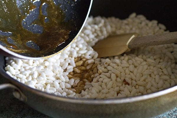 adding jaggery solution to roasted puffed rice. 