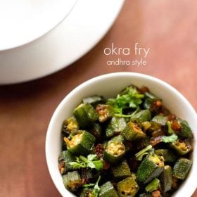 bendakaya fry garnished with coriander leaves and served in a white bowl with text layover.