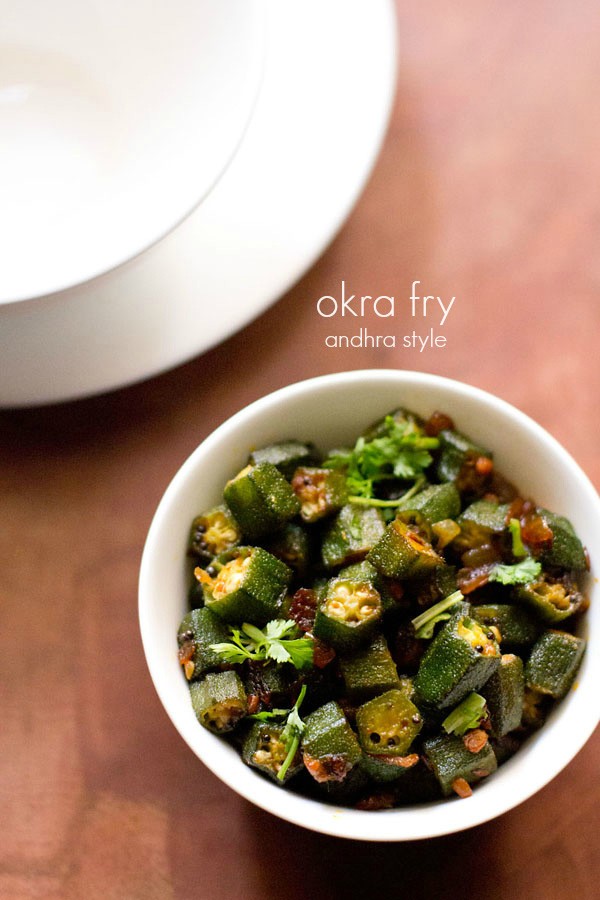 bendakaya fry garnished with coriander leaves and served in a white bowl with text layover.