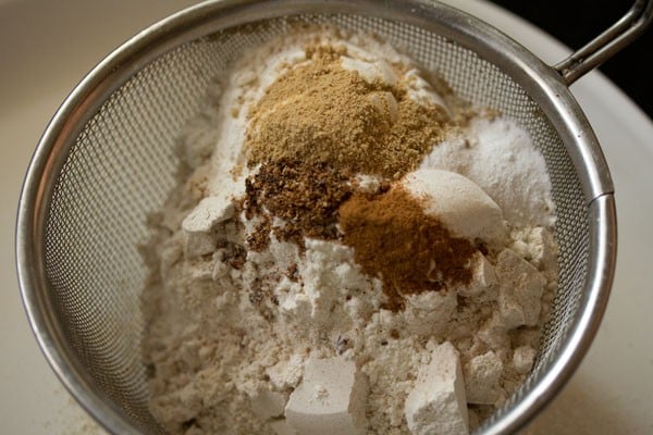 dry ingredients for making whole wheat ginger cookies in a mesh strainer for sifting.