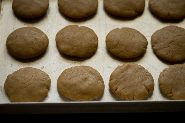 small rounds of gingerbread cookie dough pressed flat on the greased baking sheet.