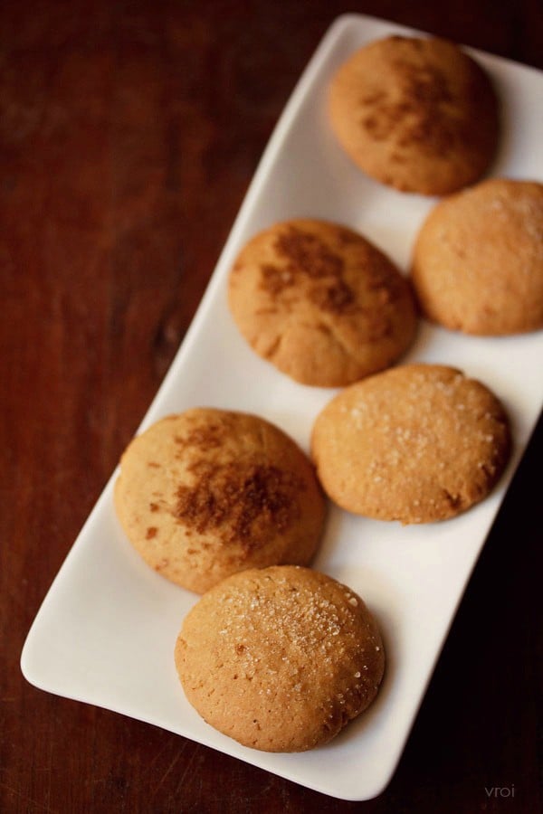 eggless gingerbread cookies with alternating brown and white sugar dusting on a rectangular white plate.