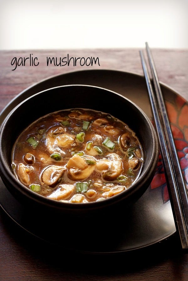 chinese mushroom in spicy soy sauce served in a black bowl with 2 chopsticks kept on right side and text layover.