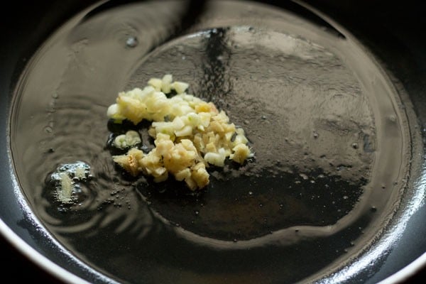 sautéing chopped garlic in hot sesame oil in a wok. 