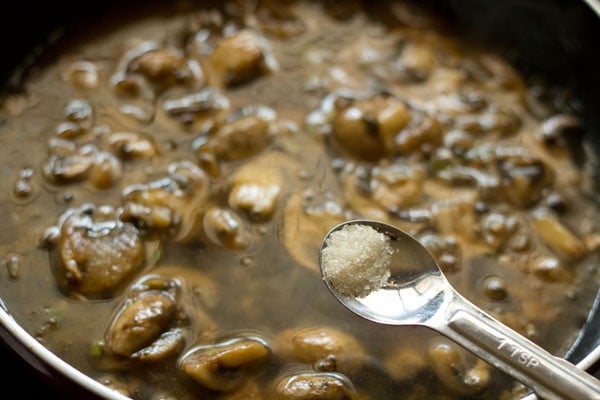 adding sugar to the mushroom mixture in the wok. 