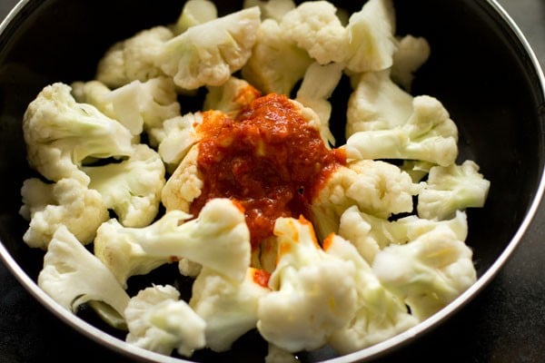red chilli paste on top cauliflower florets in black bowl