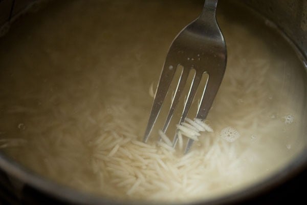 stirring the basmati rice grains with a fork. 