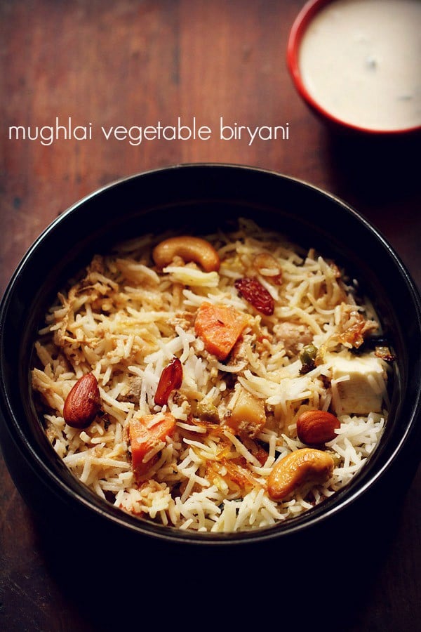 mughlai biryani served in a black handi with a bowl of raita placed in the background and text layover.