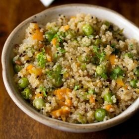 closeup shot of quinoa upma in a ceramic bowl.