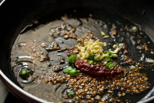 adding chiles and ginger to the hot skillet