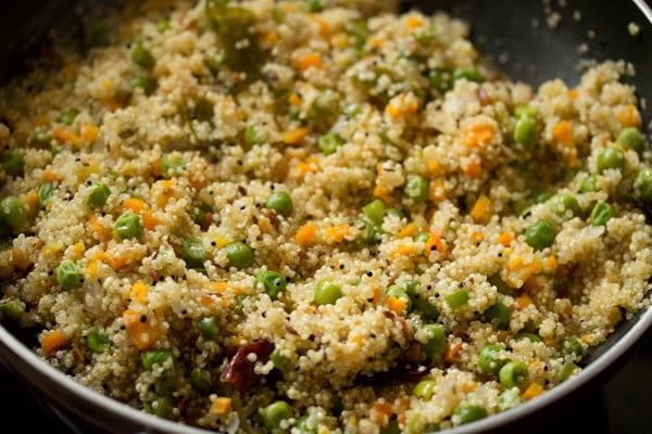 stirring quinoa upma mixture while cooking