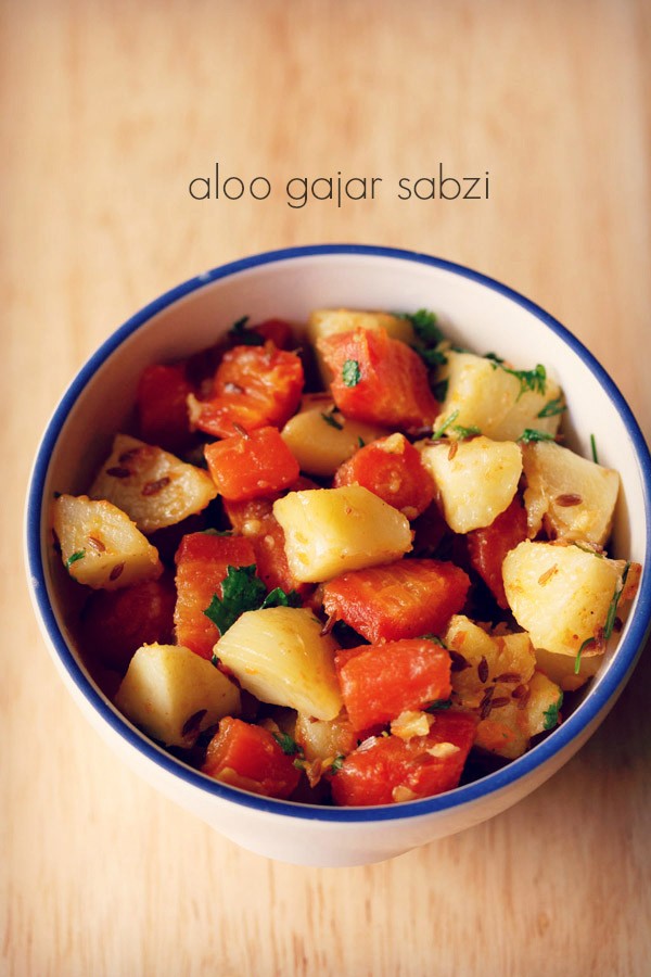 aloo gajar ki sabji served in a blue rimmed bowl with text layover.