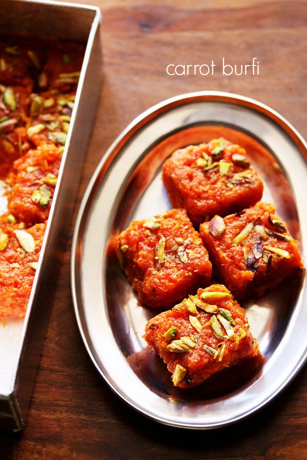 gajar ki barfi squares garnished with chopped pistachios and served on a steel plate with text layover.