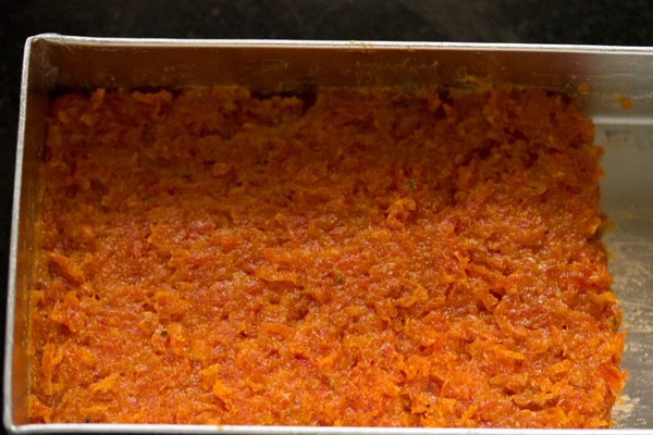 coked gajar ki barfi mixture spread in the greased tray. 