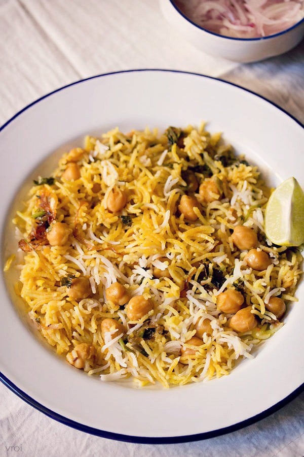 chana biryani served on a plate with a side of thinly sliced onions