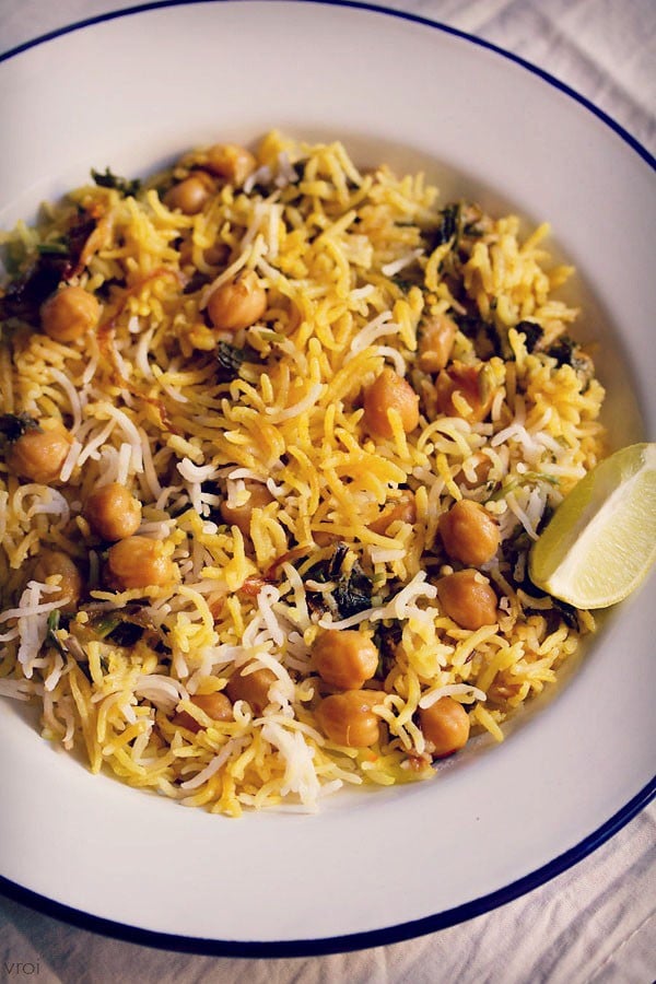 chana biryani served in a plate with a side of lemon wedges