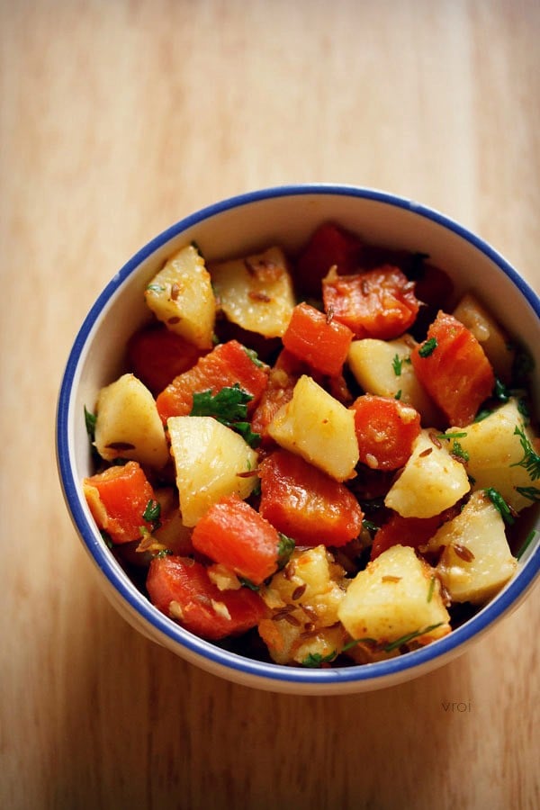 aloo gajar ki sabji served in a blue rimmed bowl. 