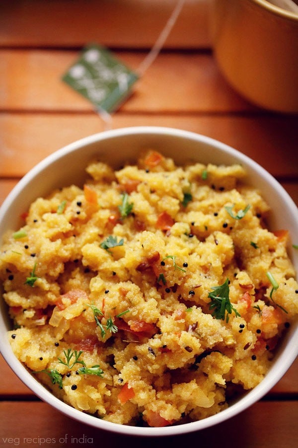 tomato upma served in a bowl with a side of tea