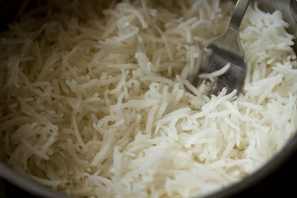 fluffing the cooked rice with a fork. 