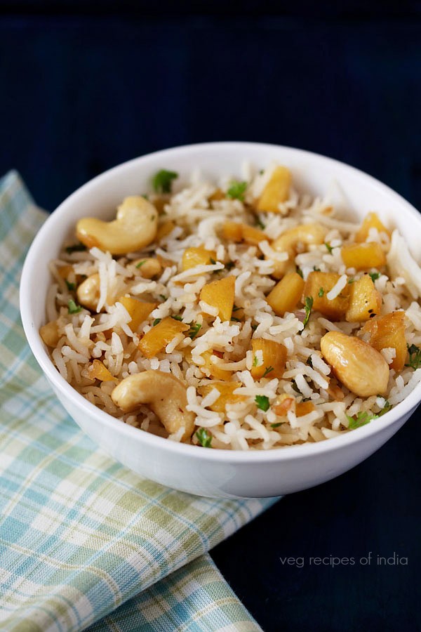 thai pineapple fried rice served in a bowl kept on a checkered napkin. 