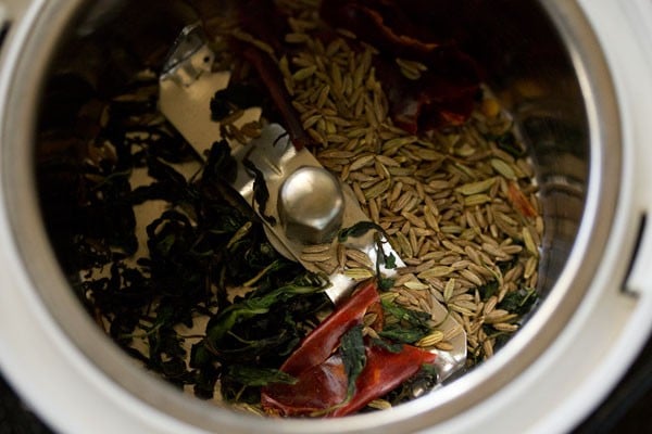 cumin seeds and fennel and red chili added to grinder jar