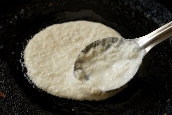 spreading rava uttapam batter on tawa