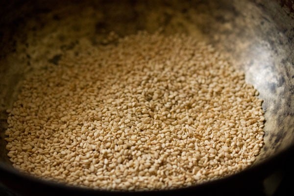 white sesame seeds added to a hot pan for making sesame laddu. 
