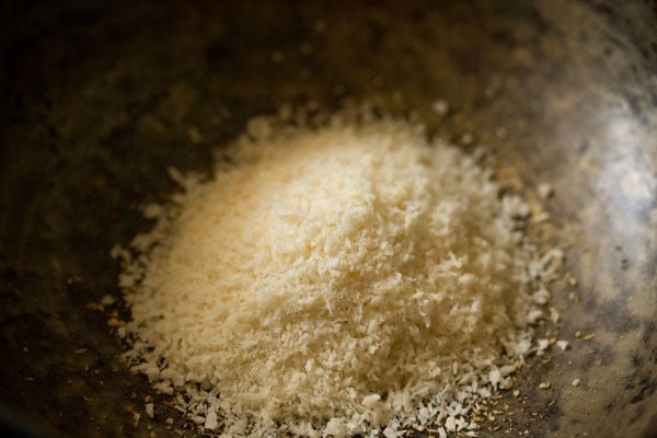 desiccated coconut added to the hot pan for making sesame laddu. 