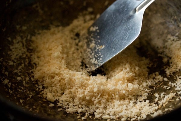 stirring and roasting desiccated coconut for making sesame laddu. 