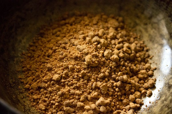 jaggery powder added to hot pan for making jaggery syrup. 