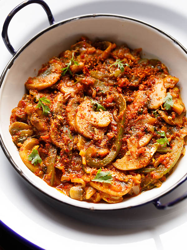 instant pot kadai mushroom gravy served in a white enamel kadai on a  white enamel plate