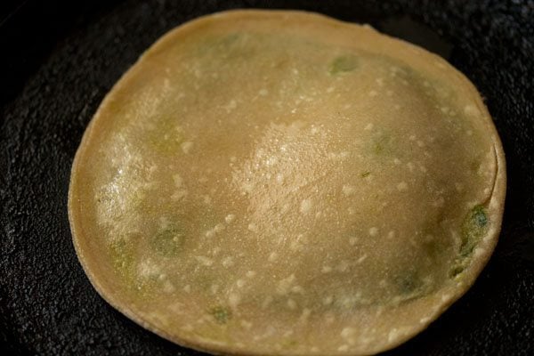 applying ghee on peas paratha