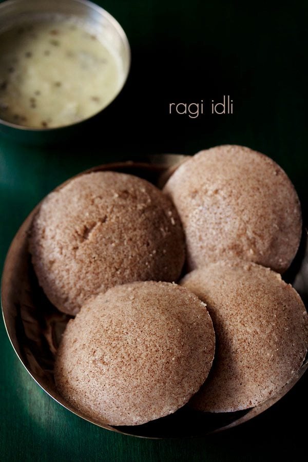 ragi idli served in a bowl with a bowl of coconut chutney on the top and text layovers.