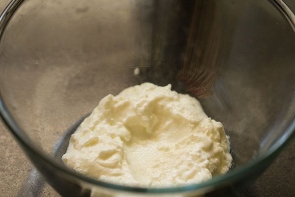hung curd added in a bowl for marinade of tandoori aloo recipe. 