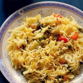 pressure cooker biryani on a white plate with a purple and golden design on the rim.