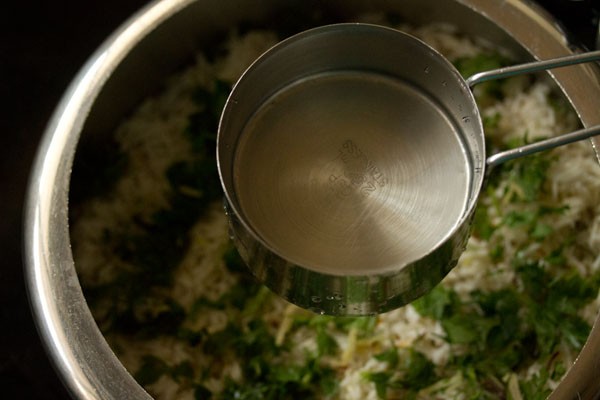 adding water into the layered vegetable biryani. 