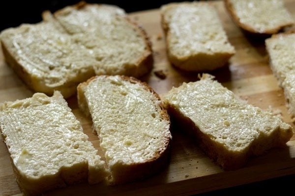 mantequilla de ajo untada en rebanadas de pan partidas a la mitad. 