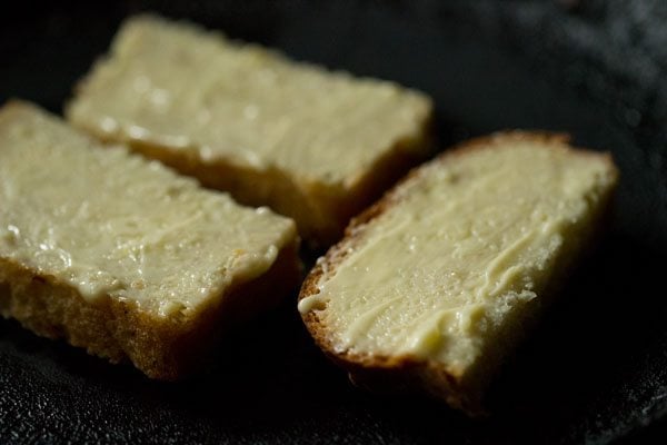 rebanadas de pan con mantequilla colocadas en un tawa caliente. 