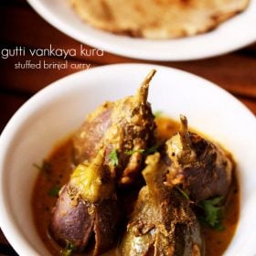 gutti vankaya garnished with coriander leaves and served in a white bowl with a plate of chapatis kept in the background and text layover.