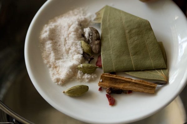 adding spices and salt to water from a white plate.