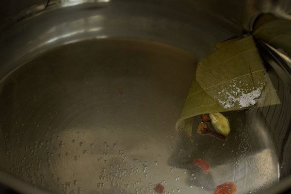 spices floating in water in pan.
