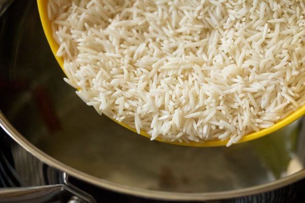 adding basmati rice from bowl to water in the pan.