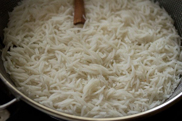 par-cooked basmati rice in colander.