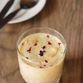 lauki ki kheer garnished with crushed dried rose petals and served in a glass with text layover.